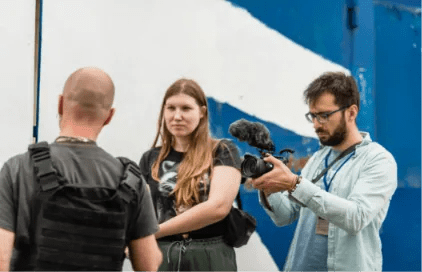 Film students and an instructor working on location with a camera rig and microphone while exploring film production software for students.