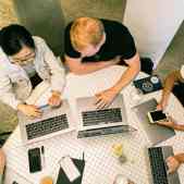 researchers collaborating around laptops in a library