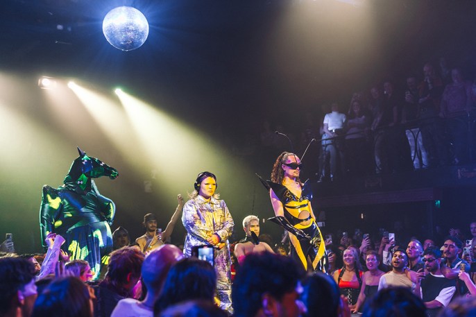 4th Annual Alexander Ball - 2 Several people in costume including one wearing a horses head are on a catwalk. There is a disco ball above them and there is a large audience watching.
