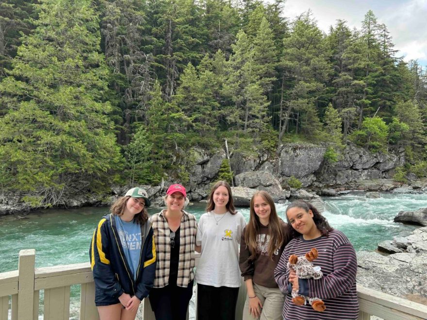UTC's UReCA production team stand in front of a lake at Glacier National Park. From left: Anna Melby, editor-in-chief; Dr. Jayda Coons, faculty advisor; Ainsley Henderson, editor; Ellie Minneci, managing editor; and Ally McCoy, editor. 