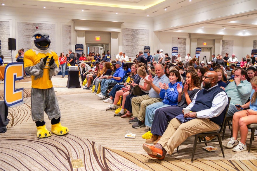 Scrappy stands in the front of the ballroom in front of hundreds of guests at a Power C Tour stop