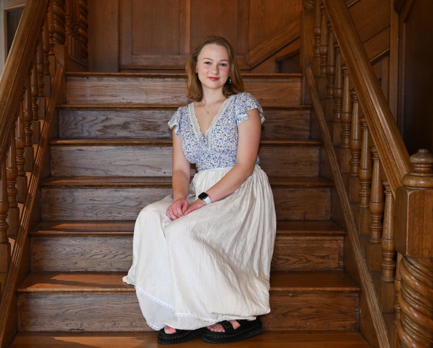 Sofiia Skrypkar sits on wooden steps in the Guerry Center.