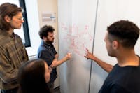 Group of engineers discussing data on a whiteboard during a team meeting.