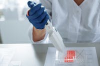 Close-up of a scientist using a pipette in a lab with a focus on sterile procedures.