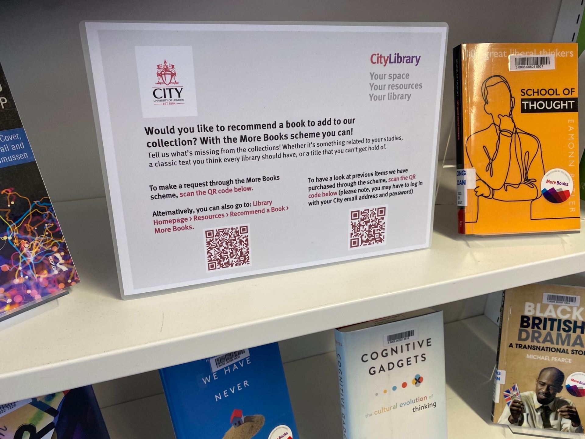 Bookshelves with book display; among the print books there is a sign with QR codes that take users to the More Books request form (https://libraryservices.city.ac.uk/resources/new-purchase-request/more-books) and a page where there are lists of books purchased via the different book recommendation schemes (you might be asked to log in with your City details to view) - https://libguides.city.ac.uk/purchases