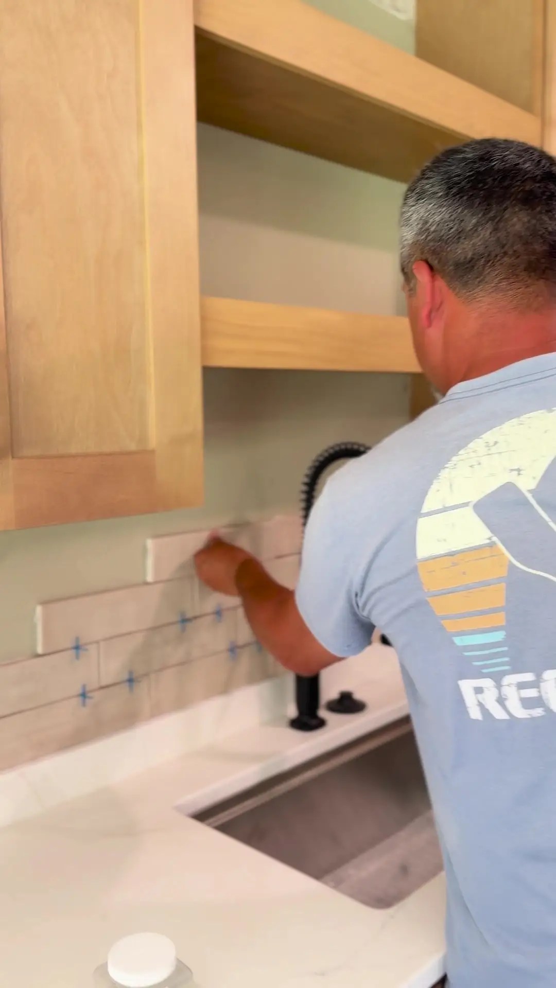 Installer setting backsplash tile above the kitchen sink during the Poquoson renovation