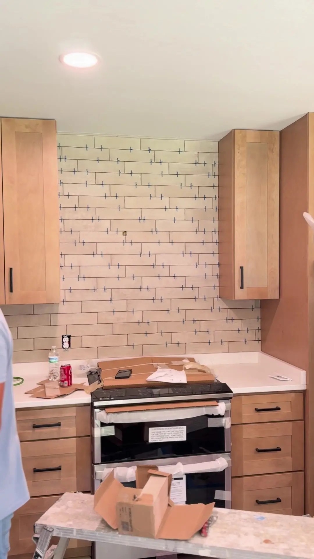 Wood kitchen cabinets, a wrapped range, and backsplash tile with spacers during the Poquoson remodel