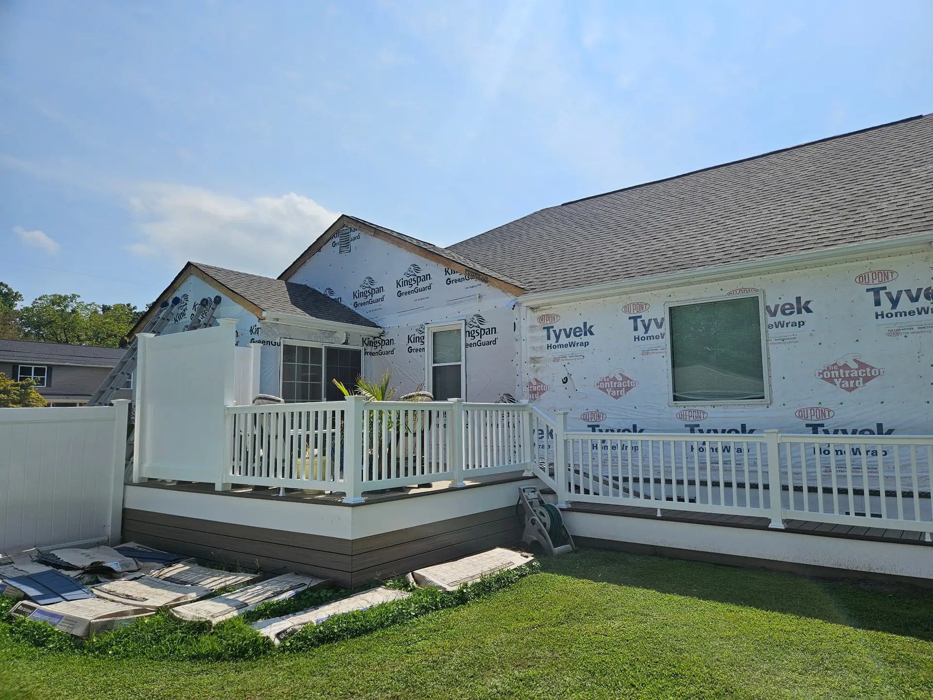 Rear of the Poquoson home with house wrap exposed beside the existing white railed deck.
