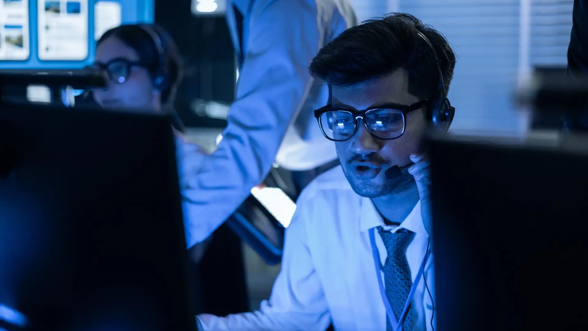 IT-Spezialist mit Headset reagiert nachts im Security Operations Center auf einen Sicherheitsvorfall