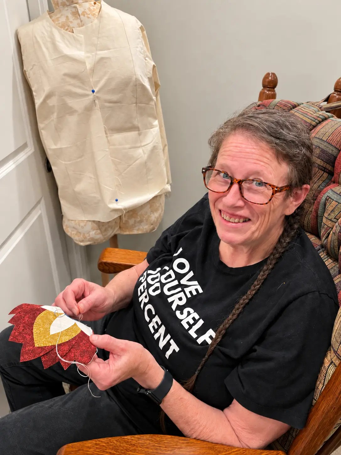 A woman with a hopeful smile hand-stitching a red and gold appliqué motif for a Finnish–Southwestern wedding quilt