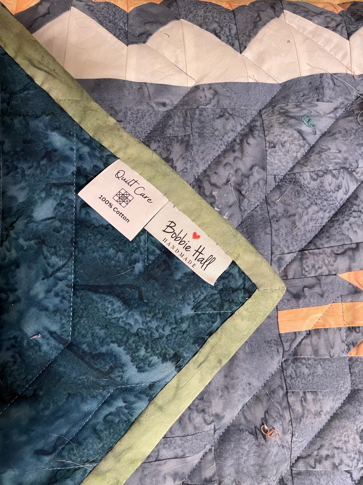 A River Runs Through quilt corner finished with green binding and a mitered corner