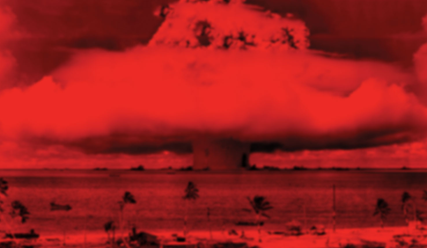 Image artwork from the cover of Ruined by Design featuring a red filtered view of the atomic mushroom cloud explosion on a small ocean island