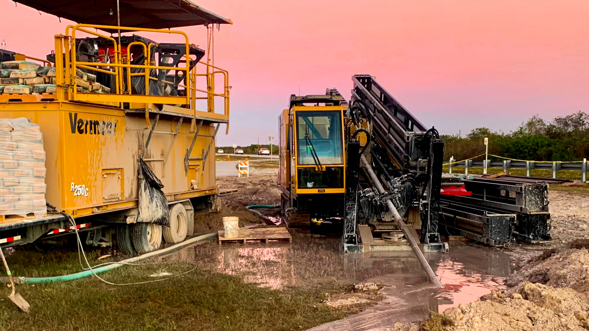 Boland South heavy construction equipment drills into a trench. The Florida sun is setting in the background.