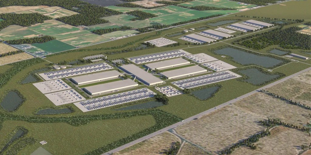 Aerial view of the Meta Hyperion JV AI megacenter, a large industrial complex with rectangular buildings, parking lots, and surrounding trees nestled amid green fields and a rural landscape. Roads and ponds are visible around the facility.