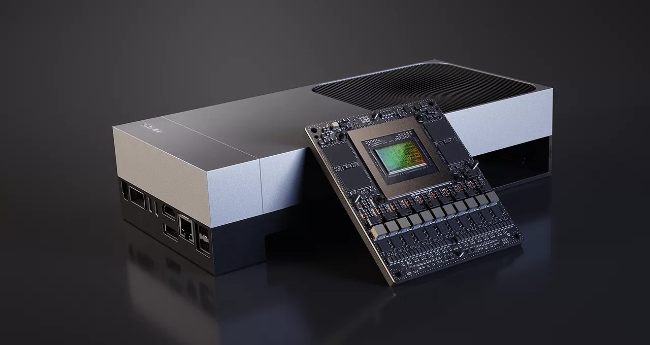 A rectangular, silver-and-black electronic device sits on a dark surface with a large computer chip—possibly Jetson Thor—leaning against it, displaying intricate circuitry and a central green processor. Several ports suggest a workstation for robotics enthusiasts.