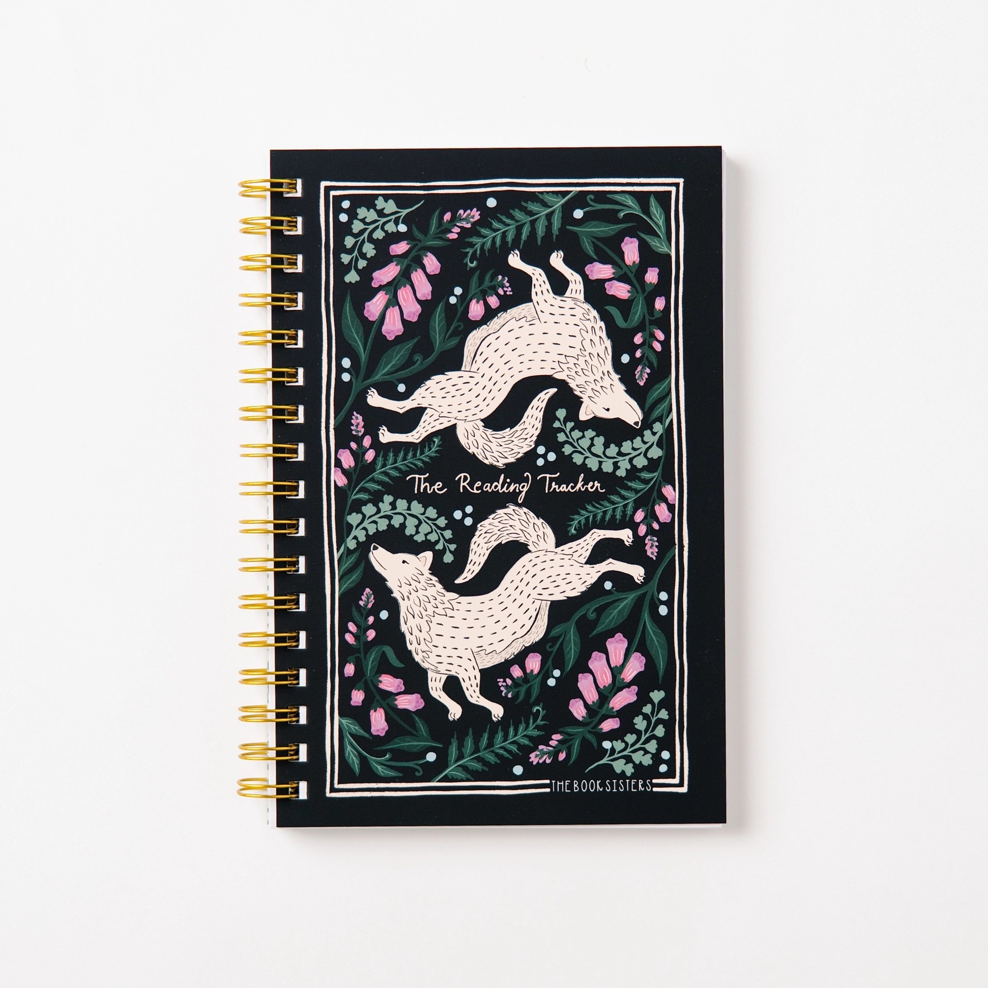 The Reading Tracker spiral notebook in black with cream wolf illustrations and pink wildflowers, gold wire binding, by The Book Sisters