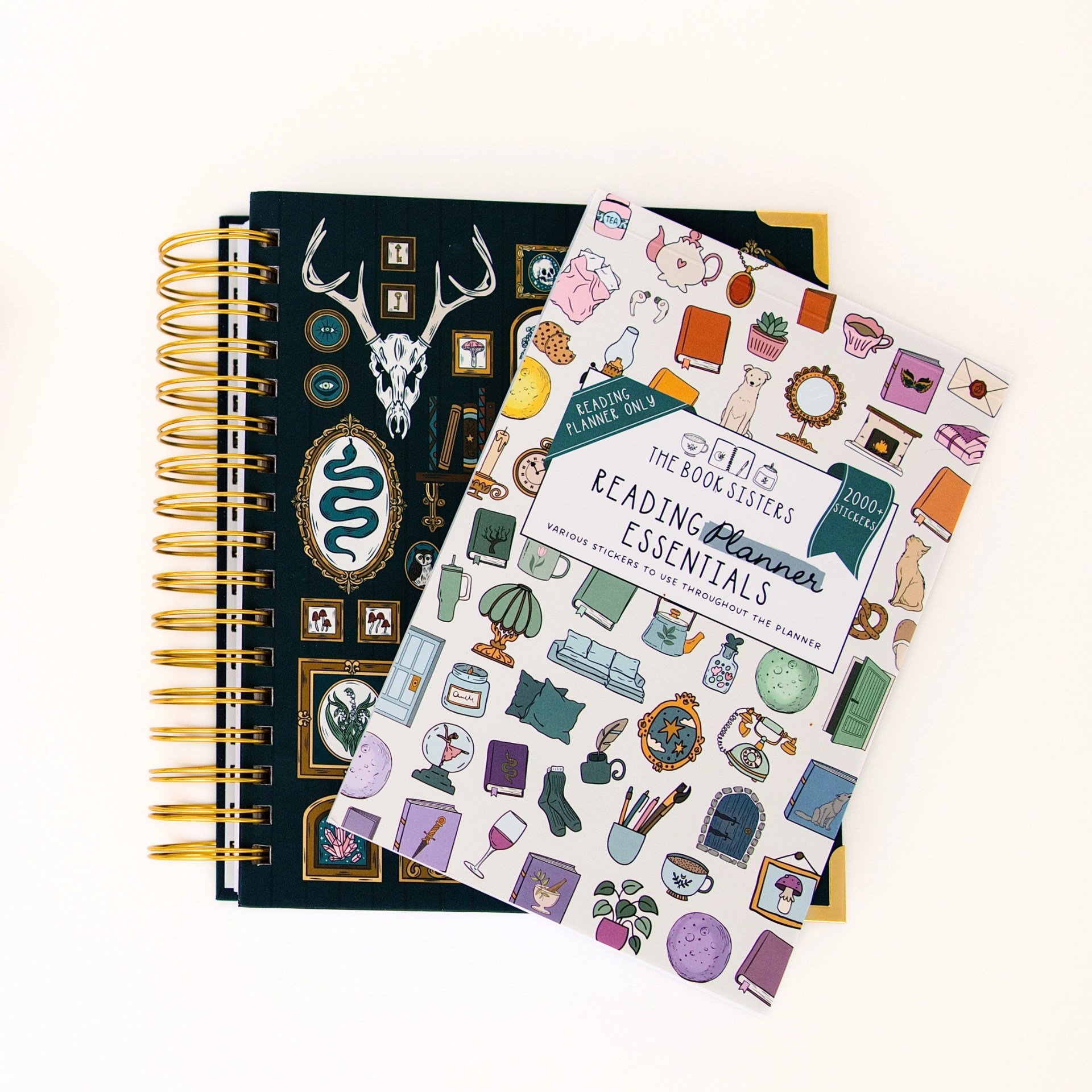 Reading Planner Essentials sticker book laid on top of a dark witchy Book Sisters reading planner with antler and skull cover art.