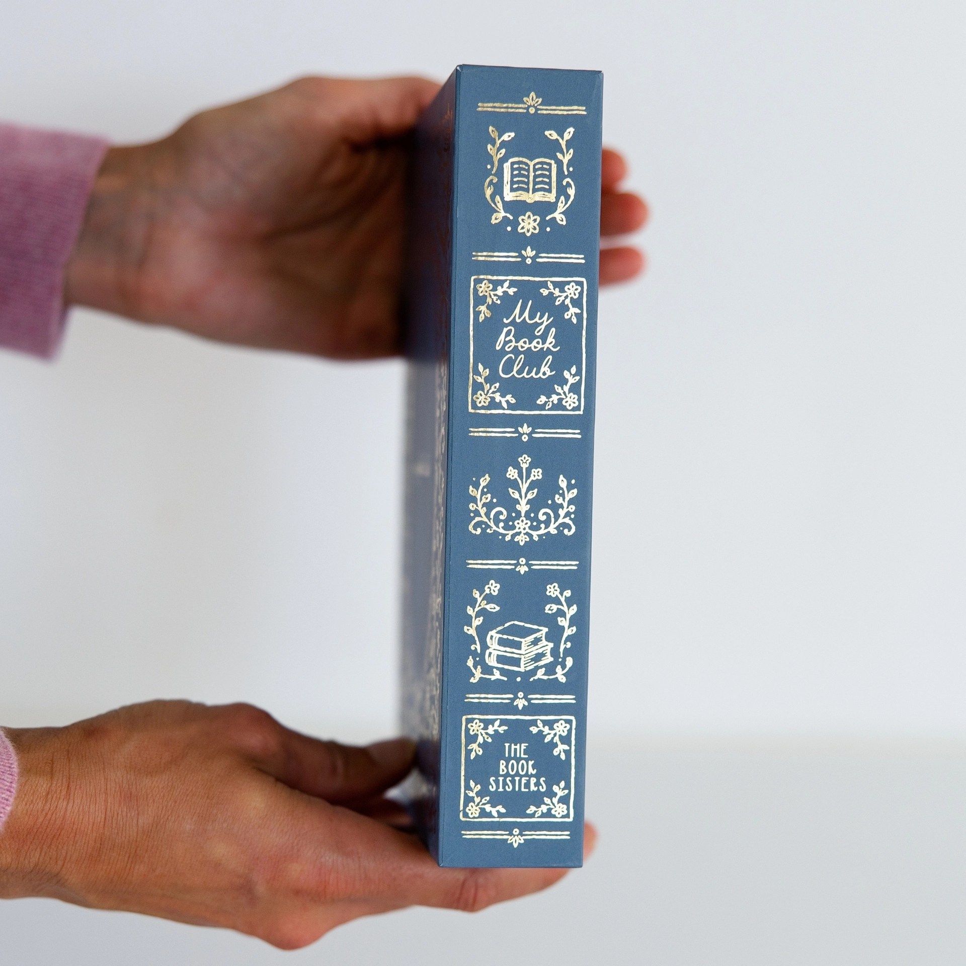 Hand holding the My Book Club journal upright showing its gold foil spine details.