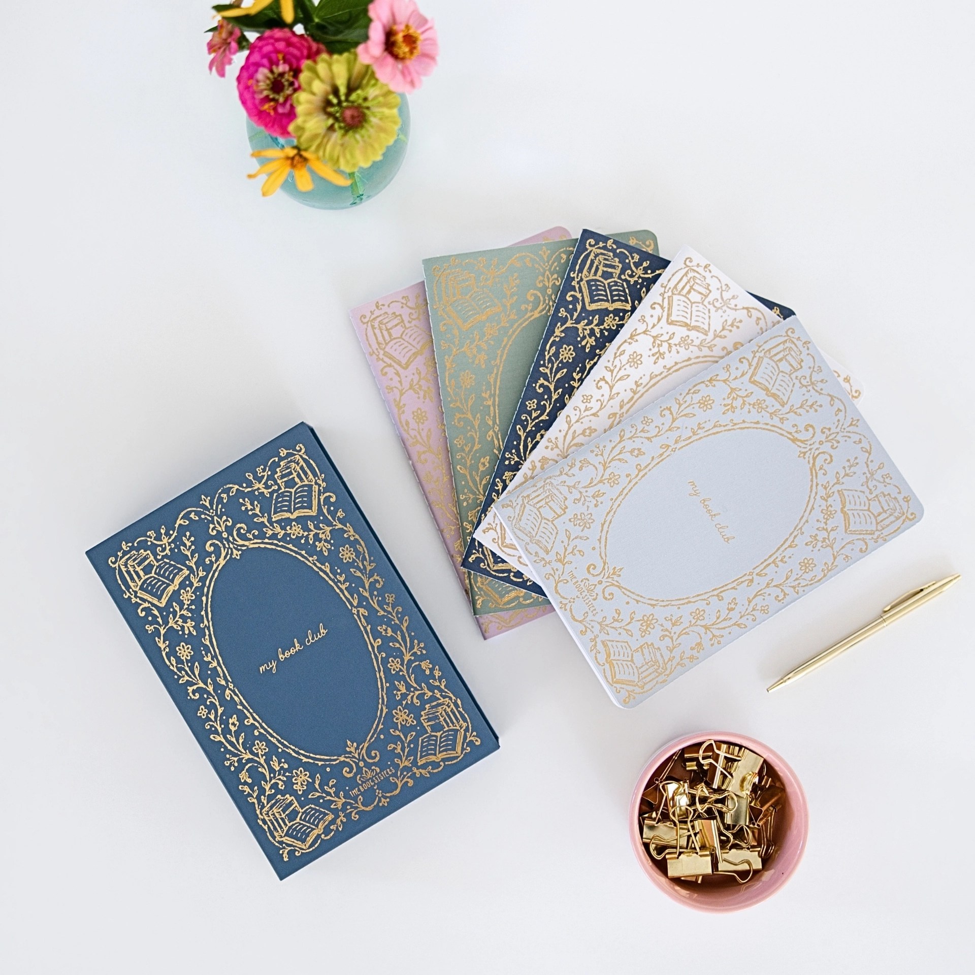 My Book Club journal box, fanned journal colors, Book Talk card deck, open journal, gold pen, and clips with fresh flowers.