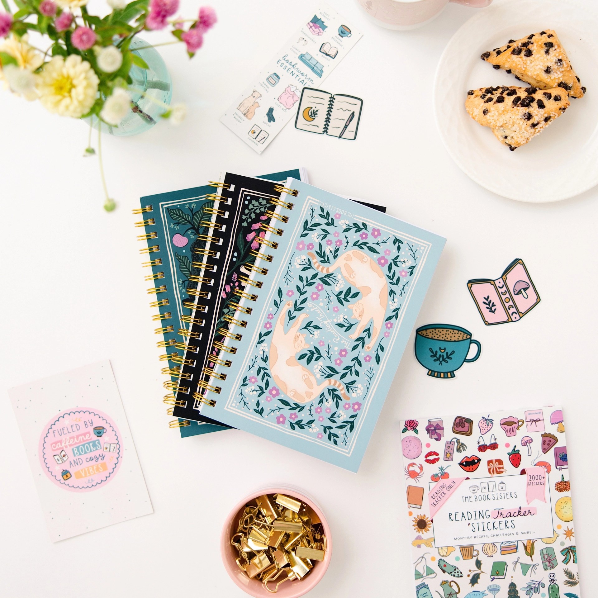 The Reading Tracker notebooks in three cover designs styled with reading tracker stickers, flowers, and a scone