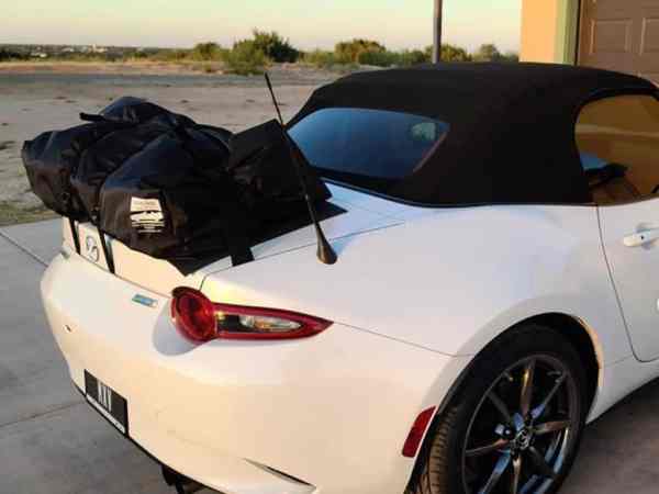 white mazda miata mx5 nd on a driveway at dusk with. boot-bag vacation luggage rack fitted to the trunk