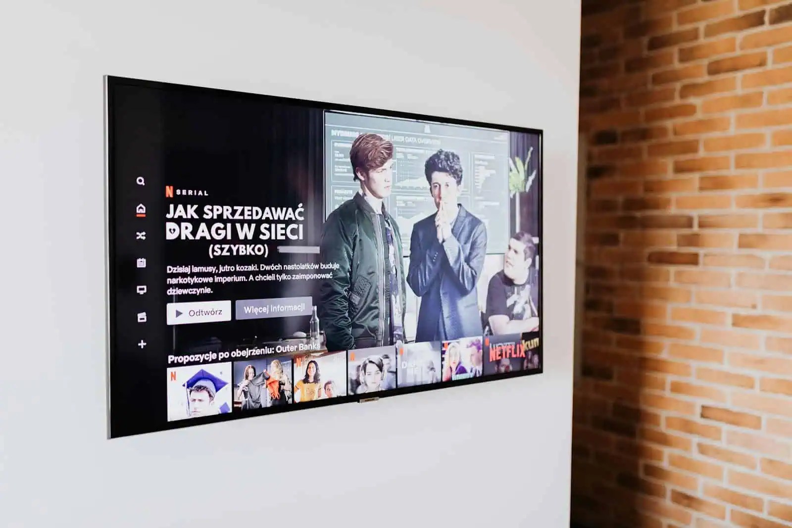 Smart TV displaying streaming content in modern living room setting with exposed brick wall.