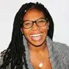 A powerful woman with long, intricately braided hair and stylish glasses flashes a confident, unstoppable smile. Rocking a sleek gray sweater against a crisp white background, she radiates bold leadership and undeniable Boss Uncaged energy—effortlessly blending style, strength, and entrepreneurial spirit for the modern go-getter. - Boss Uncaged™ OmniMedia Inc.