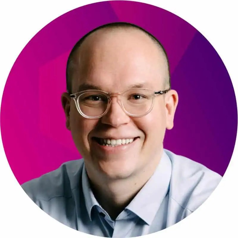 Chris Cownden rocks glasses and a light blue shirt, smiling boldly before a bold purple-pink cyber security-themed backdrop. - Boss Uncaged™ OmniMedia Inc.
