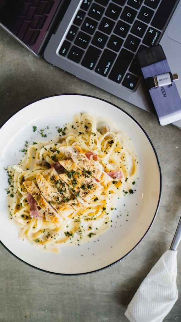Delicious creamy pasta Alfredo with grilled chicken served in a white bowl, perfect for a cozy meal.