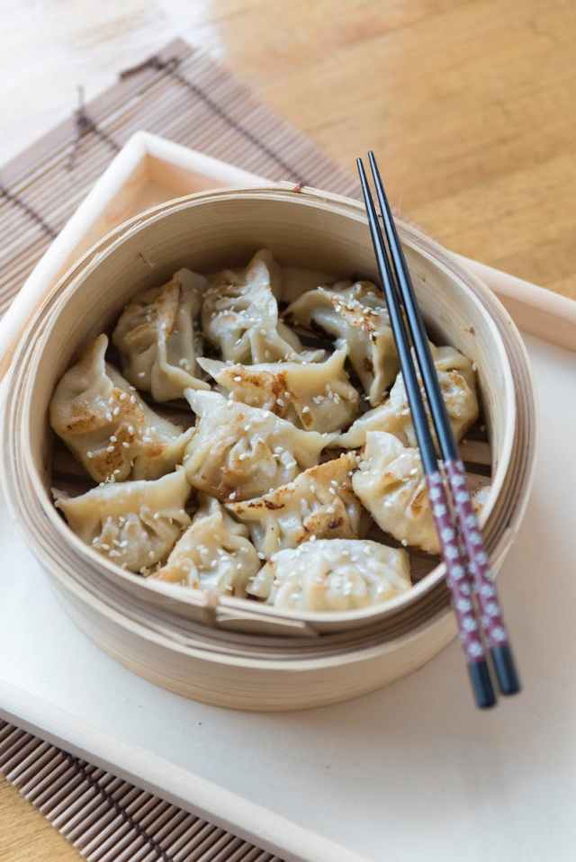 Savory homemade dumplings served in a traditional bamboo steamer with chopsticks.