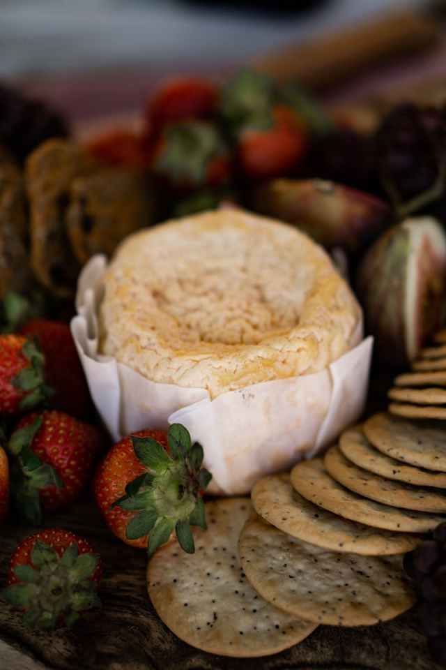 Gourmet cheese platter featuring ripe strawberries, figs, and assorted crackers, ideal for elegant entertaining.
