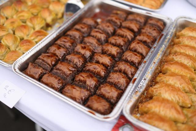 Close-up of assorted baklava and pastries in trays, ready for sale at a market.