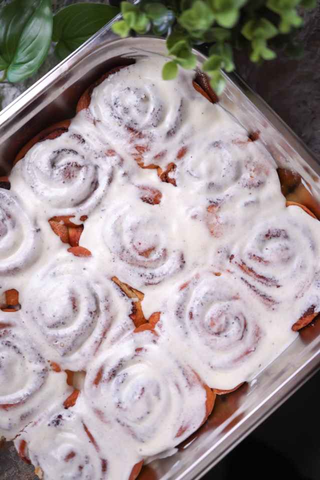 A tray of hot cinnamon rolls drizzled with creamy icing, perfect for breakfast.