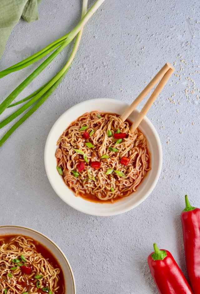 Flat lay of spicy ramen noodles in a bowl, garnished with vegetables. Perfect for Asian cuisine enthusiasts.
