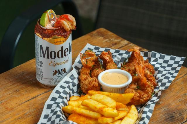 A delicious combo of crispy fried shrimp and fries paired with a Modelo beer.