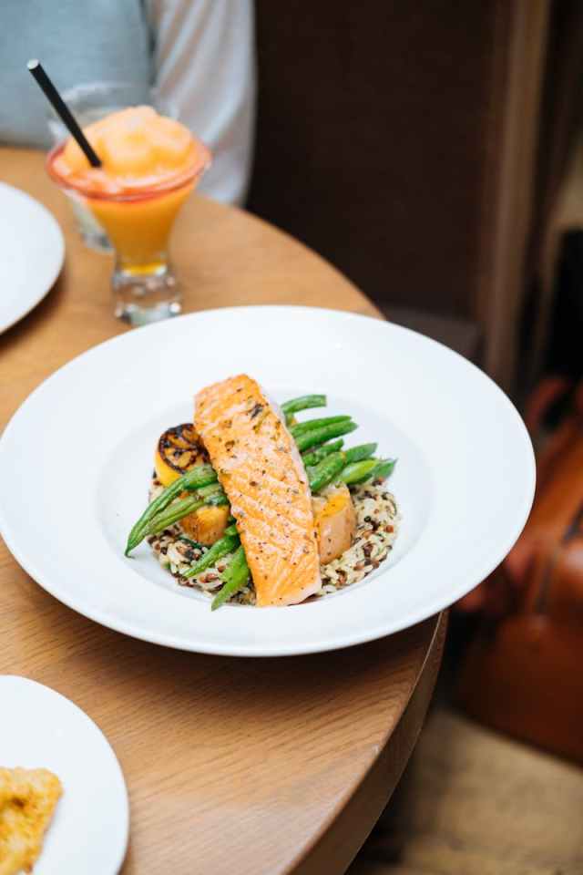 Grilled salmon served with quinoa, asparagus, and squash on a round table setting.