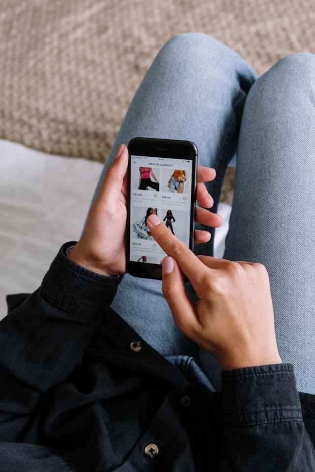 Close-up of a woman shopping online on a smartphone while relaxing at home.