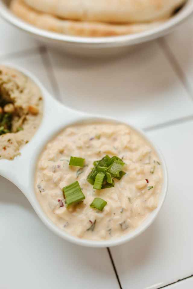 Close-up of a creamy dip garnished with green onions, perfect for appetizers.