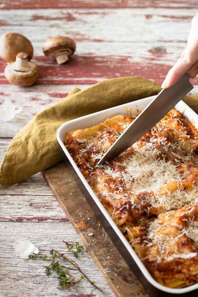 Appetizing homemade lasagna with cheese and herbs being sliced, ready to serve.