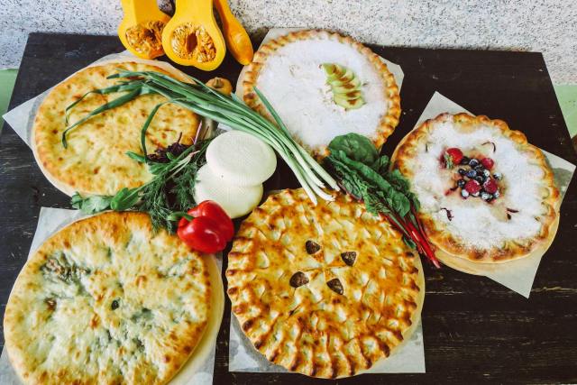 A high-angle view of various pies with fresh vegetables, showcasing a mix of savory and sweet flavors.