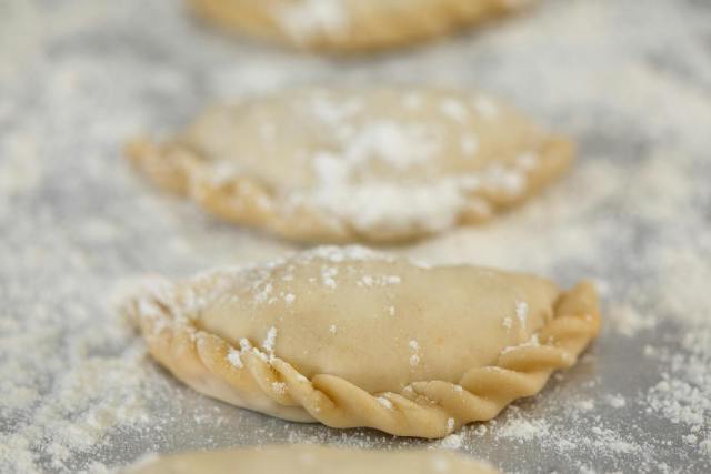 Freshly prepared empanadas on a floured surface, highlighting the baking process.
