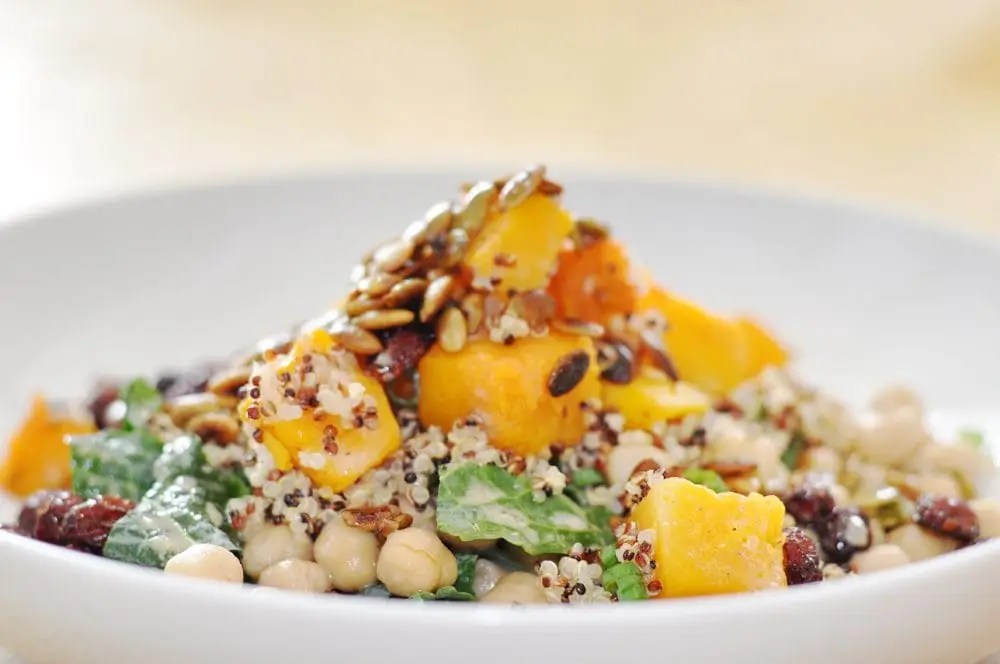 Plate of butternut squash salad with kale, quinoa, and mint tahini dressing