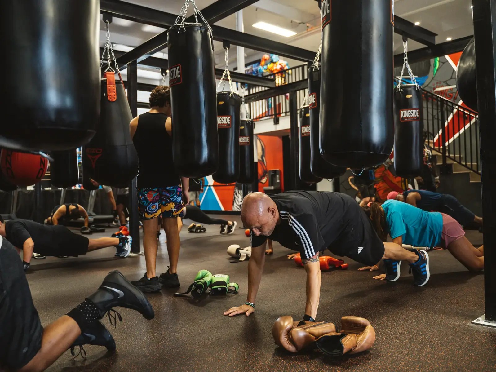 Group class doing push-ups between heavy bags