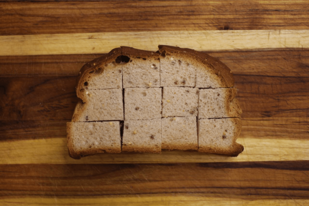 Bread cut into 1 inch pieces on cutting board
