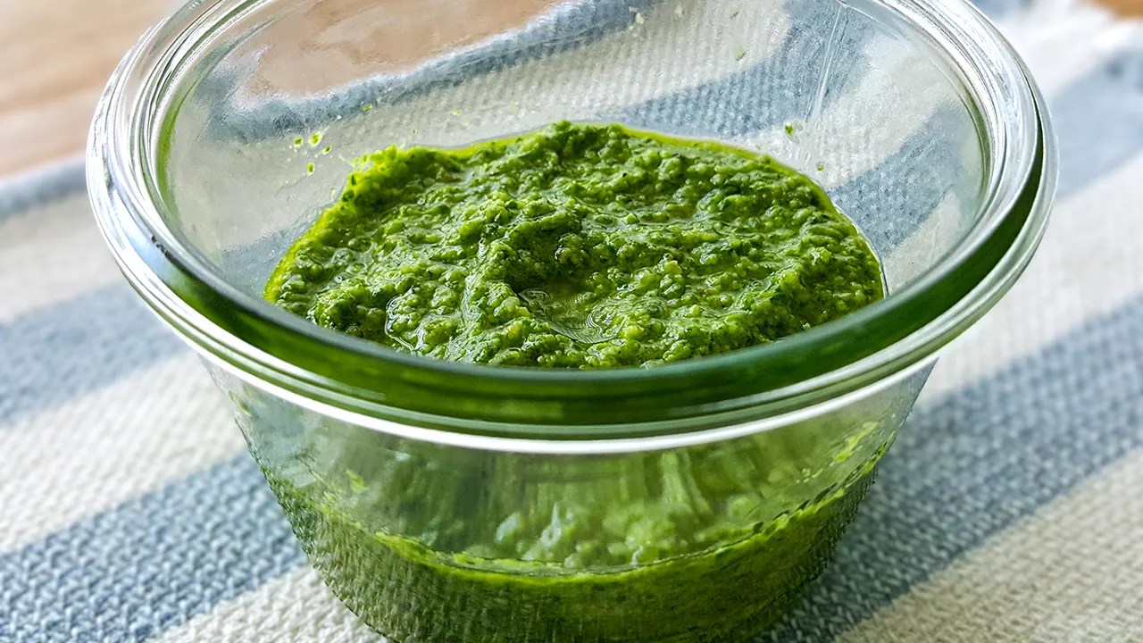 Clear glass bowl containing spinach and basil pesto sauce