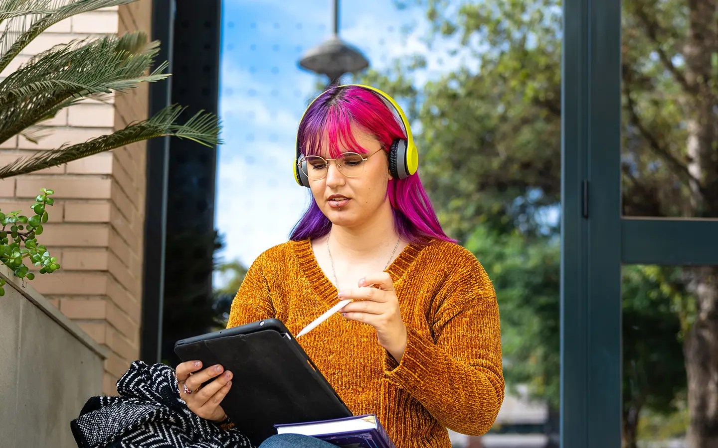 Female college student with headphones on, using an iPad