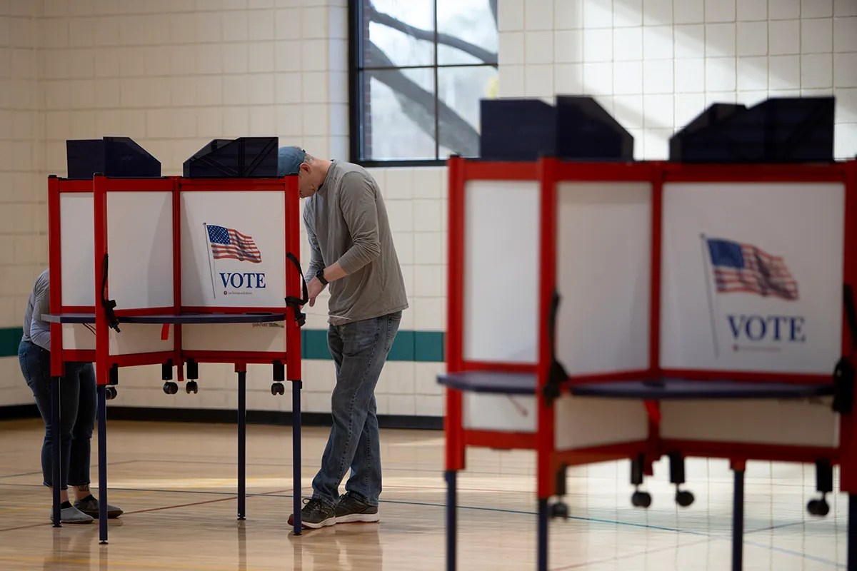 People casting their votes in booths.