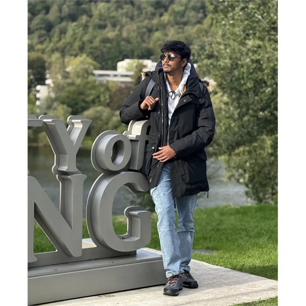 Nivas wears a suit jacket and smiles at the camera