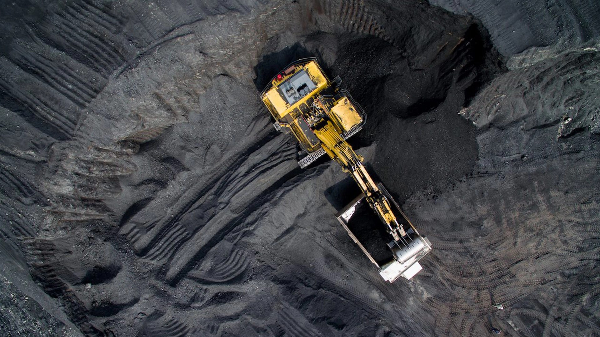 Aerial view of a large excavator loading mined material into a haul truck at an open pit mining operation in botswana