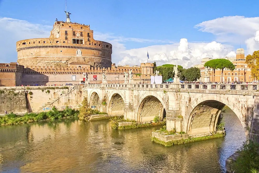 View of an ancient bridge of a river leading up to a round medieval castle